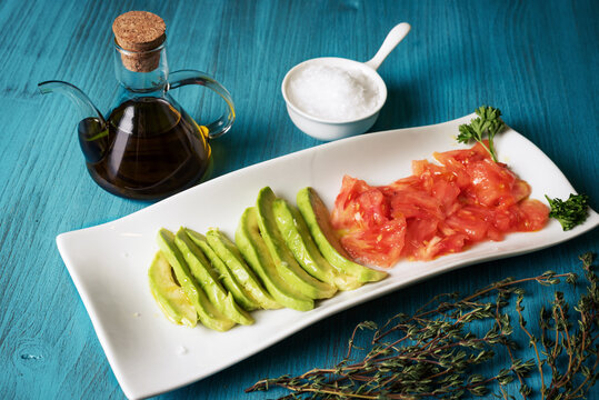 Plate to snack with avocado and tomato accompanied by oil and salt flakes.