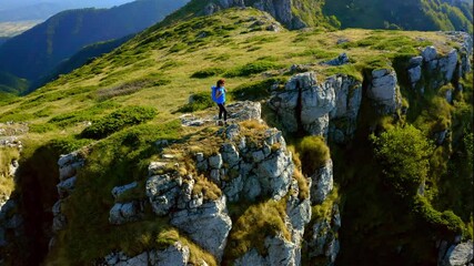 Aerial view of a woman on top of a mountain looking at the sunrise. Hiker girl celebrating scenic landscape enjoying nature vacation travel adventure. 4k