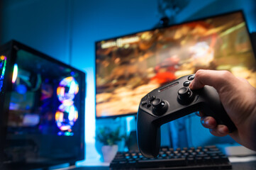 Girl gamer plays a video game with friends. She has a gamepad in her hand. Large monitors of two computers. Fun entertainment, win, winners, esports, computer communications. © Anton