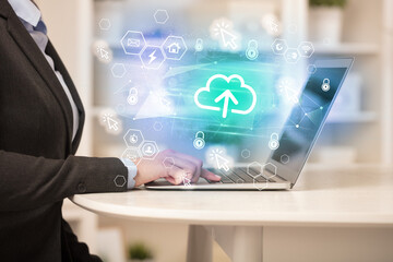 Hands working on laptop with digital icons