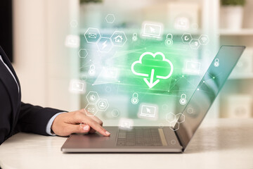 Hands working on laptop with digital icons