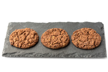 Three granola cookies on a stone board for serving.