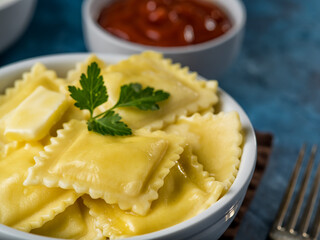 macro photography. Portion of Italian ravioli with a sprig of parsley and tomato sauce in the background. Dark blue background. Minimalism. Restaurant, hotel, food design, advertising.
