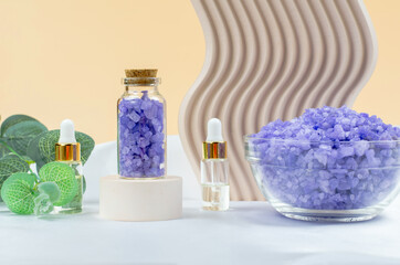 Fototapeta na wymiar Lavender sea salt in a transparent bottle on a round podium. SPA composition.