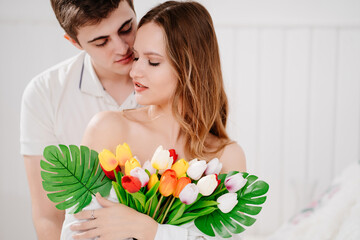 a man gave his beloved woman a bouquet of colorful tulips. tender embrace.