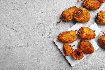 Many tasty dried persimmon fruits on light table, flat lay. Space for text