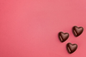 three heart shaped chocolates on pink paper