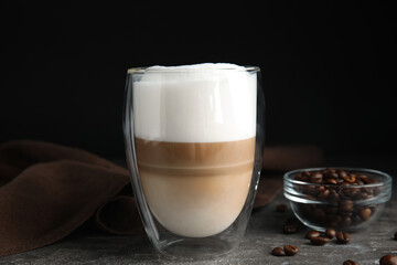 Delicious latte macchiato and coffee beans on grey table