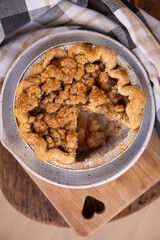 Homemade mini apple crumble pie on cutting board with slice taken out