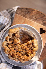 Homemade mini apple crumble pie on cutting board with slice taken out