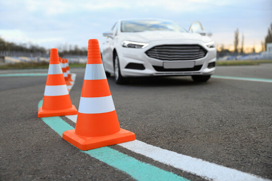 Modern car at test track, focus on traffic cone. Driving school