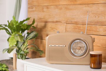 Stylish beige radio on white table near wooden wall indoors, space for text