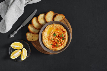 Traditional Middle east appetizer Hummus served with fresh pita bread and herbs, with olive oil and paprika in vintage ceramic plate on the wooden desk. top view, copy space