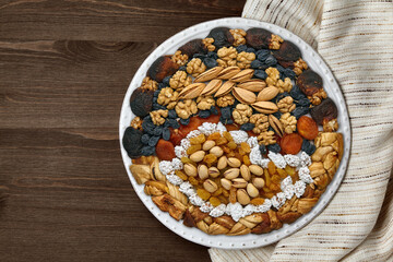 Plate with dried fruits, candied fruits and nuts on a bright kitchen towel