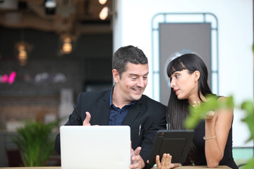 two young business people working and communicating while standing at the office with city building background.