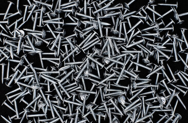 scattered metal screws on a black background