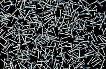 scattered metal screws on a black background