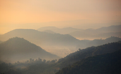 Mountain range with visible silhouettes through the morning colorful fog.with sunlight romanctic moment