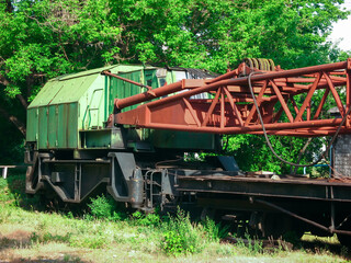 Fototapeta na wymiar railway crane stands on abandoned tracks near trees 