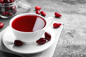 Obraz na płótnie Canvas Cup of fresh dogwood tea and berries on grey table. Space for text