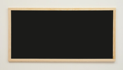 Clean black chalkboard hanging on white wall