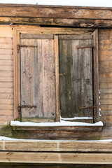 Abandoned wooden house with closed window in winter day, Talsi, Latvia