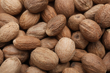 Heap of nutmeg seeds as background, top view