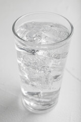 Glass of soda water on white table, closeup