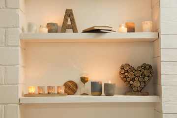 Burning wax candles and different decor on shelves