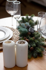 Christmas tree branches with cones on the dining table. Glasses on the table.