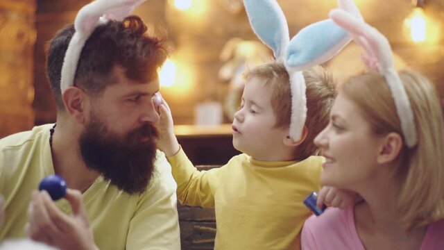 Happy family of mother, father and child son painted Easter eggs, wearing bunny ears on Easter day. Funny cute kids face.