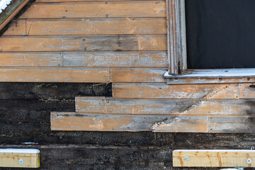 An old, historic wooden house is being restored in winter day