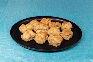 Fresh baked biscuits filling a black plate on a table