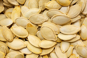 Background photo of pumpkin seed kernels. Close-up view of roasted pumpkin seeds. Shelled pumpkin...