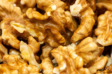 Raw walnut background. Close-up walnut kernel. Macro photo of walnuts in daylight. Walnut in top middle in selective focus.