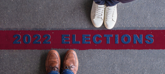 2022 elections illustration. Two people standing opposite each other, divided by a red line and their political preferences. - obrazy, fototapety, plakaty