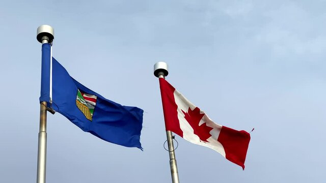 A waving Alberta Flag with the Canadian flag on a windy day