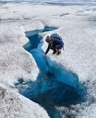 Adventure Girl hiking climbing exploring on blue glacier in Valdez Alaska and drinking water from blue pool and stream flowing on glacier © Collin