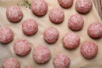 Many fresh raw meatballs on parchment paper, flat lay