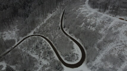 Drohnenaufnahme von kurviger Straße in verschneiter Landschaft
