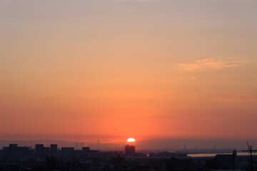 都市の夜明け。太陽が昇りあたりはオレンジ色に染まる。神戸市東灘区の高台岡本梅林公園から神戸市街地、大阪方面を臨む。