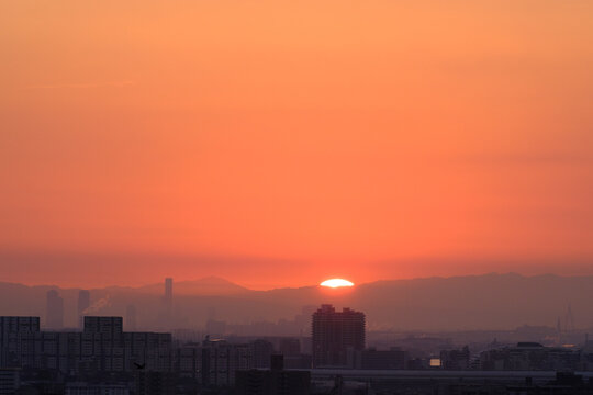 都市の夜明け。太陽が昇りあたりはオレンジ色に染まる。神戸市東灘区の高台岡本梅林公園から神戸市街地、大阪方面を臨む。 © 宮岸孝守