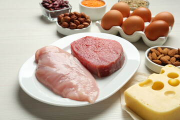Fresh meat and other products on white wooden table, closeup. Sources of essential amino acids