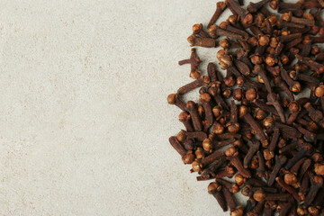 Pile of aromatic dry cloves on white table, flat lay. Space for text