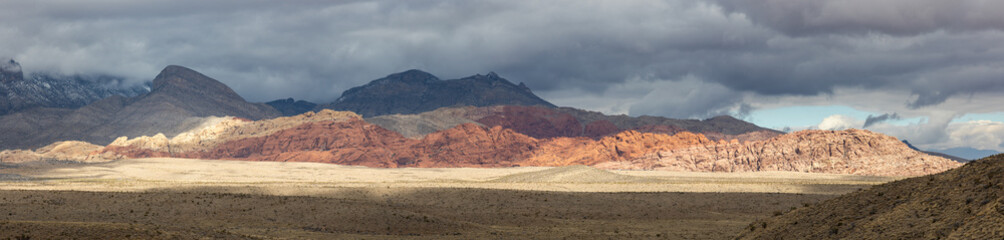 Panorama of Red Rock Canyon highlighted by sun breaking through clouds