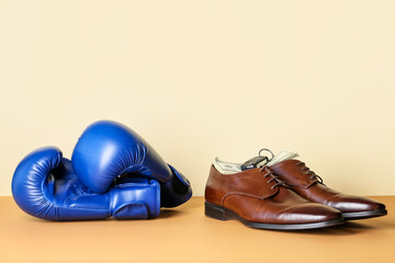 Male shoes and boxing gloves on color background. Concept of balance