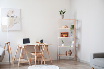 Interior of light room with modern workplace and shelving unit