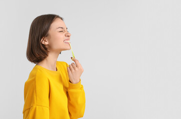 Funny young woman with chewing gum on light background