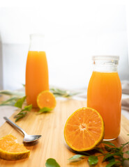 Bottles of fresh orange juice with sliced orange on wooden background