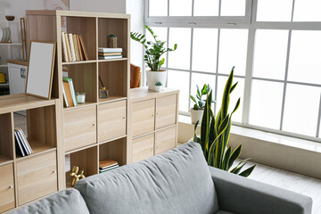 Stylish bookshelf with comfy sofa in living room
